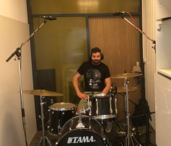 Marius sitzt am Schlagzeug und hört über Kopfhörer seine Aufnahmen